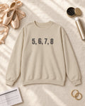 Flat lay of the 5, 6, 7, 8 Puff Crewneck in Sand