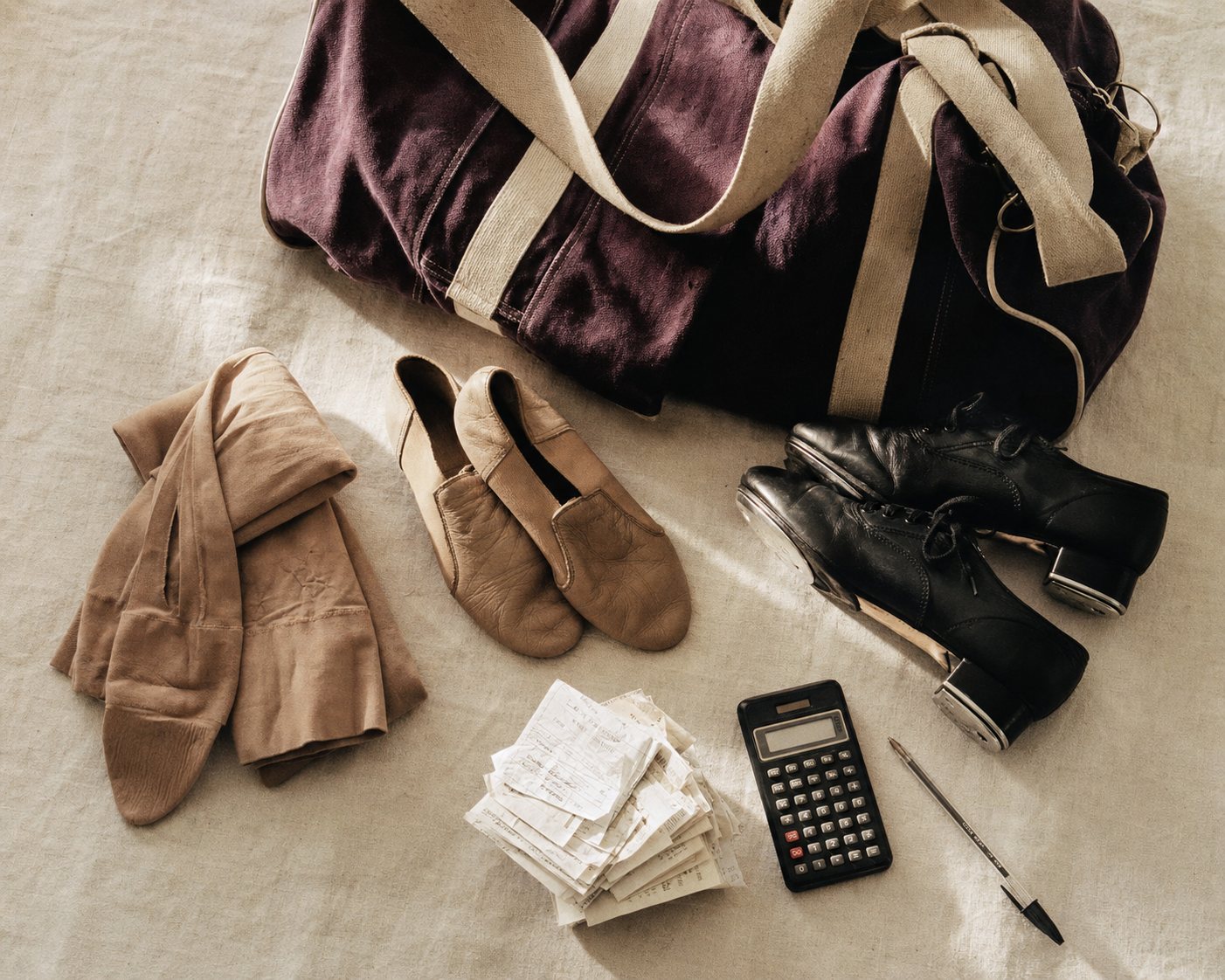 Dance duffel, tights, shoes, receipts and a calculator seen from above.